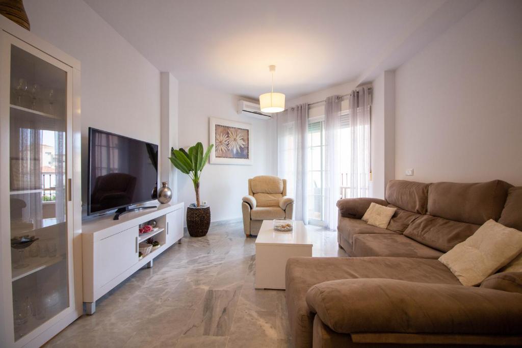 a living room with a couch and a tv at White dreams next to the sea in Algarrobo-Costa