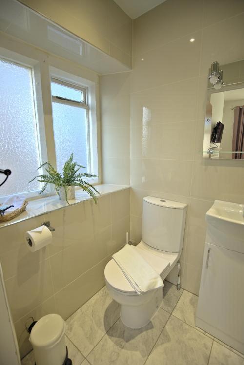 a white bathroom with a toilet and a window at Lewinsdale Lodge in Weston-super-Mare