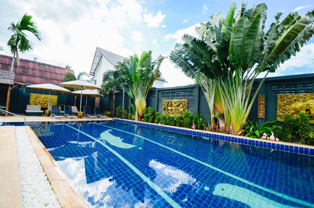 una piscina con palmeras y un edificio en Nid's Bungalows, en Chaweng