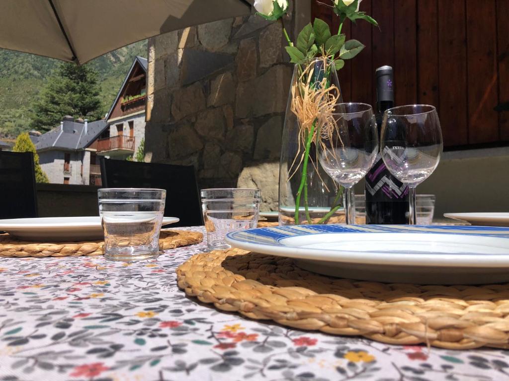 una mesa con un plato y copas de vino. en Casa Martagón - kasasbenas, en Benasque