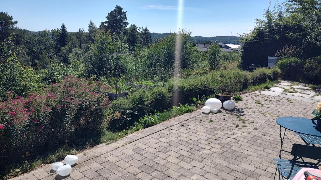 a brick patio with a garden with a table and chairs at Kaldvell Apartman in Lillesand