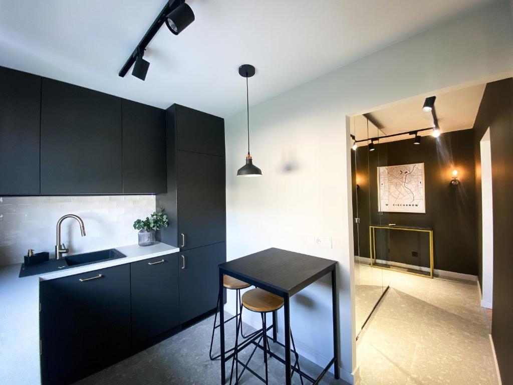 a kitchen with black cabinets and a black table at Apartament Cieszynka in Ciechanów