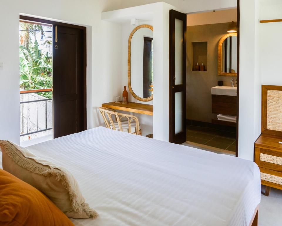 - une chambre avec un grand lit blanc et une salle de bains dans l'établissement Samba Ahangama, à Ahangama