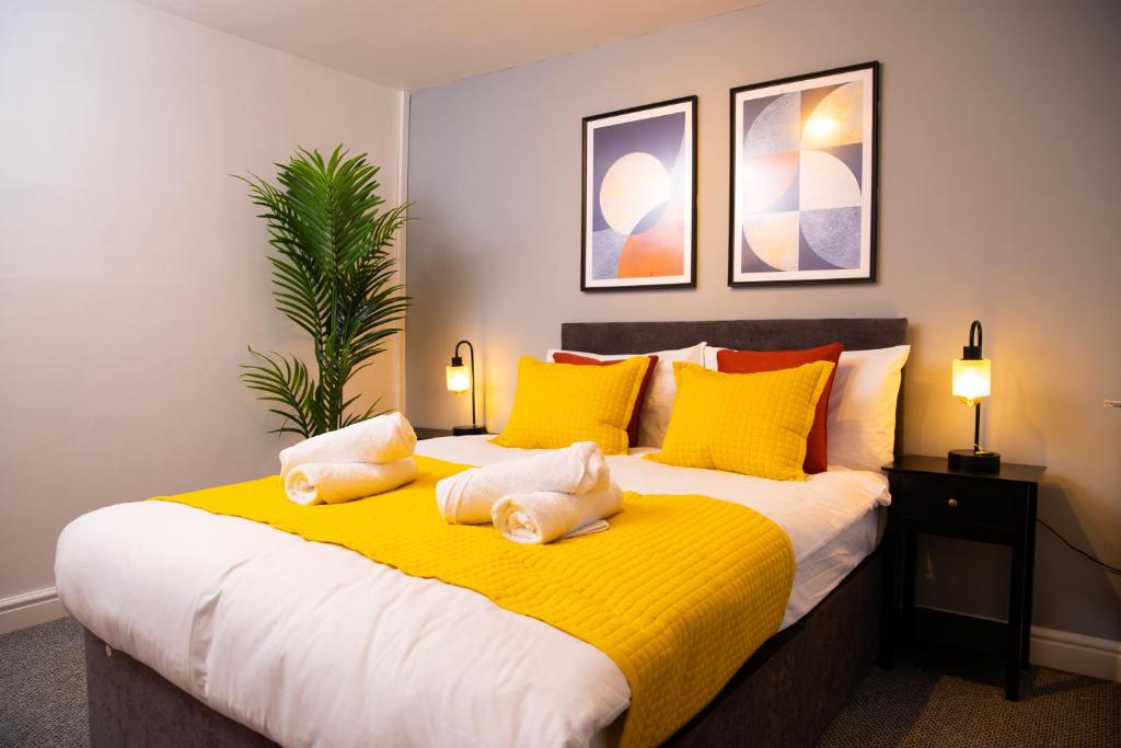 um quarto com uma cama grande com almofadas amarelas e laranja em Comfortable Stay for 6, Charming 3-Bedrooms near Gloucester Quays with Parking em Hempstead