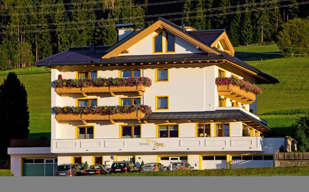 ein großes weißes Gebäude mit Blumen darauf in der Unterkunft Hotel Garni Regina in Weerberg