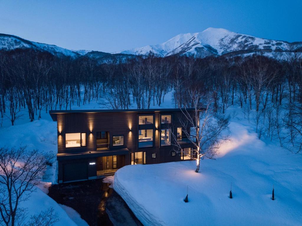 a home in the snow with mountains in the background at Song Saa Chalet in Niseko