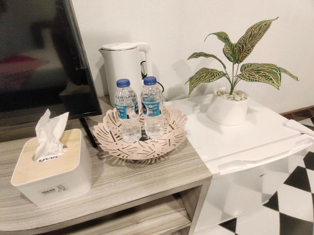 a table with two bottles of water and a plant at OYO 75446 Travis Inthamara 49 in Bangkok