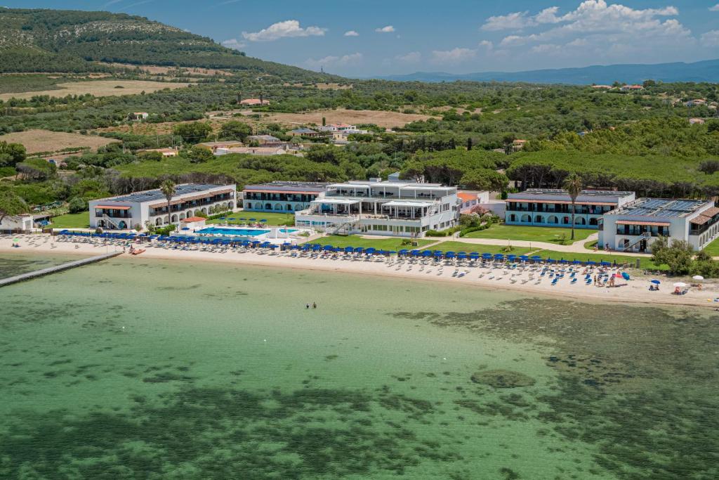 a group of people standing on a beach near the water at Hotel Portoconte in Porto Conte