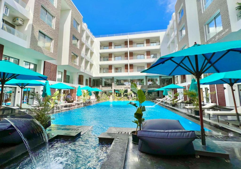 Exquisite Bali Theme Resort AC Balconys 4 Pools WIFI Included في الغردقة: مسبح فيه كراسي ومظلات في الفندق