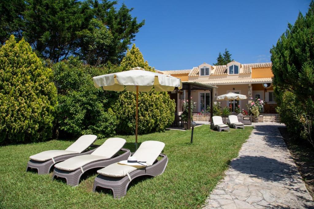a group of lounge chairs and an umbrella in the grass at Peroulades Luxury Villa in Peroulades