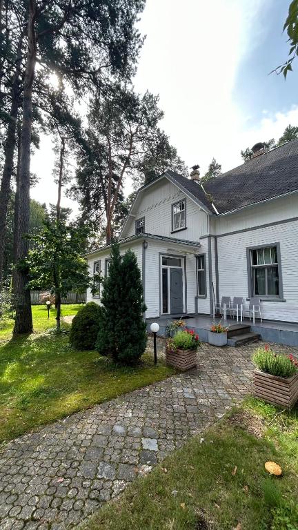 ein weißes Haus mit einer Veranda und einer Auffahrt in der Unterkunft House in Bulduri/Jūrmala nearby the beach(7min) in Jūrmala