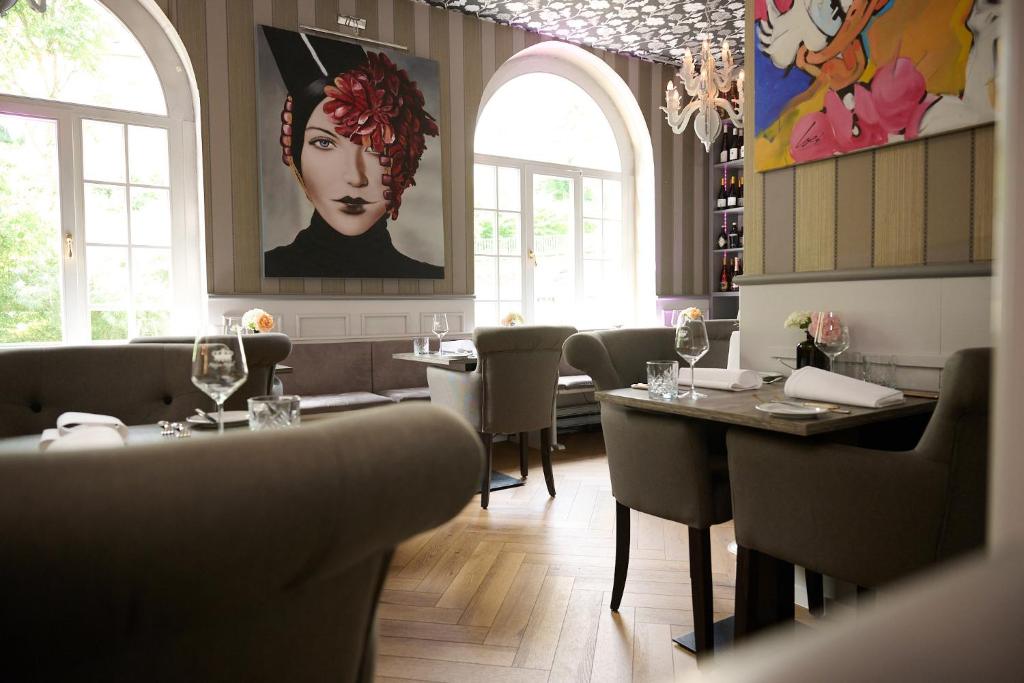 a restaurant with tables and chairs and a painting on the wall at Hotel Haus Rödgen in Wilnsdorf