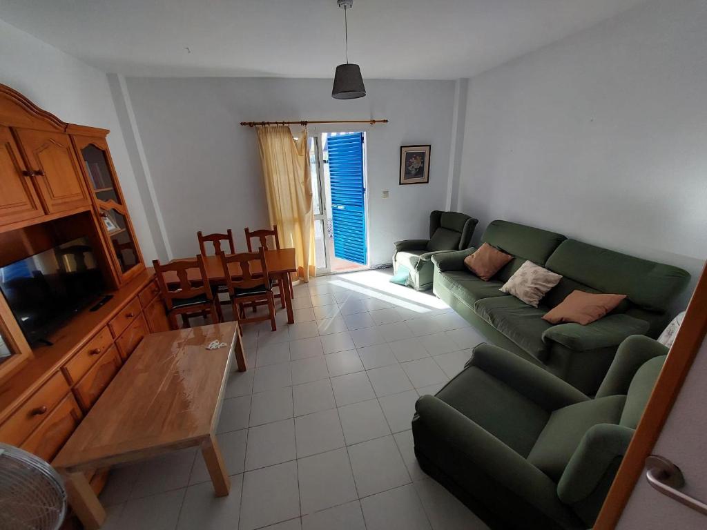 een woonkamer met een groene bank en een tafel bij La Almadraba in Novo Sancti Petri