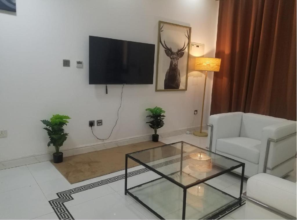 - un salon avec une télévision et une table basse en verre dans l'établissement Amazing One-Bedroom Villa TownHouse, à Dubaï