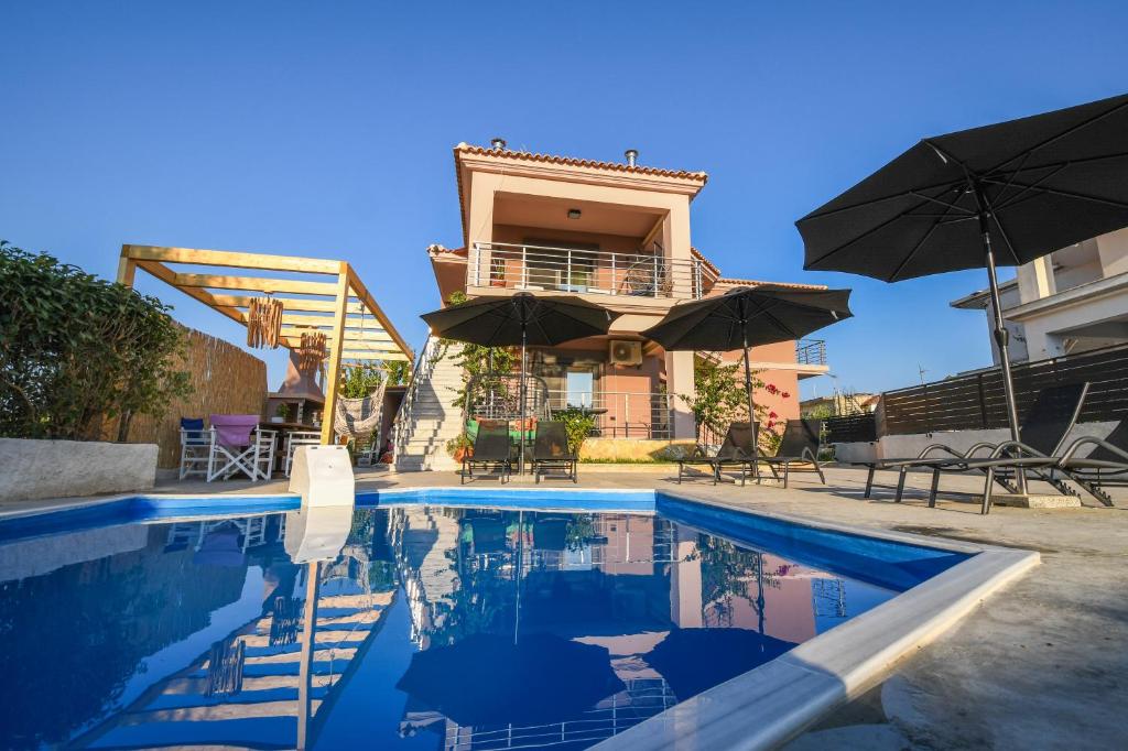 Ambelókipoi的住宿－Nektarios & Eftychia Suites，一座房子,设有一座带遮阳伞的游泳池
