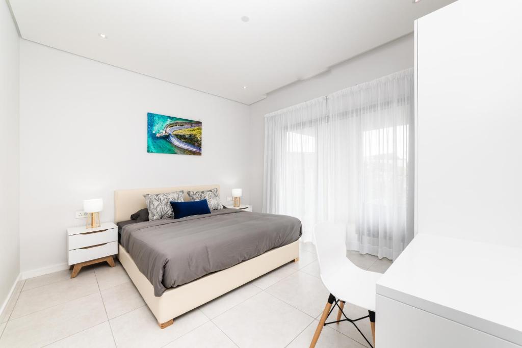 Habitación blanca con cama y ventana en Modern 2 bedroom apartment - Soleia 2 Apartment A9, en Pereybere