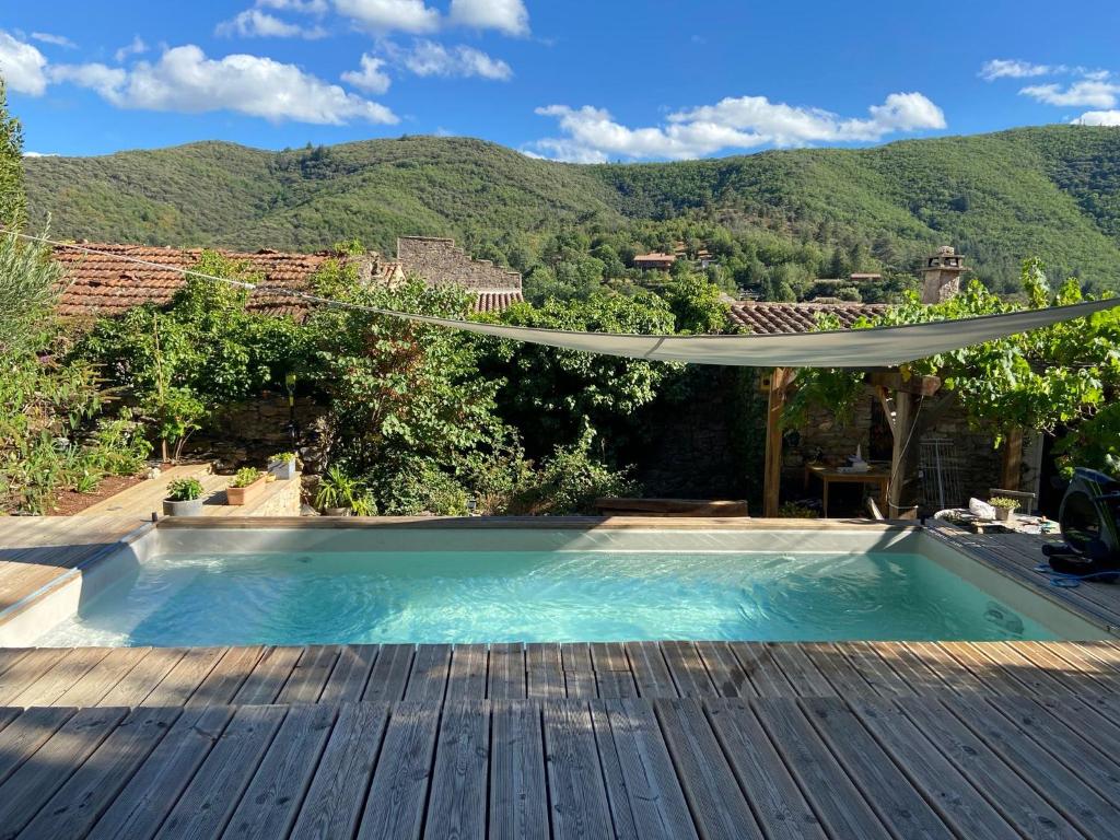 a swimming pool with a deck and mountains in the background at MAISON ST LAURENT in Olargues
