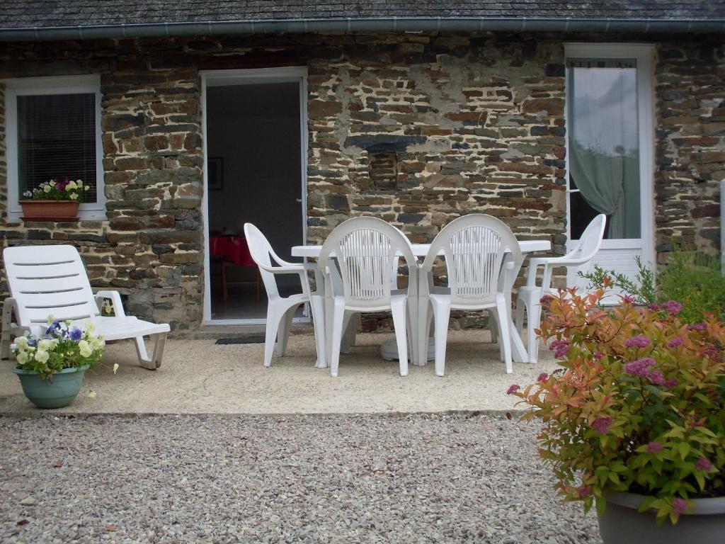 three white chairs and a table in front of a building at Gîte de Fourneaux in Pont-d'Ouilly