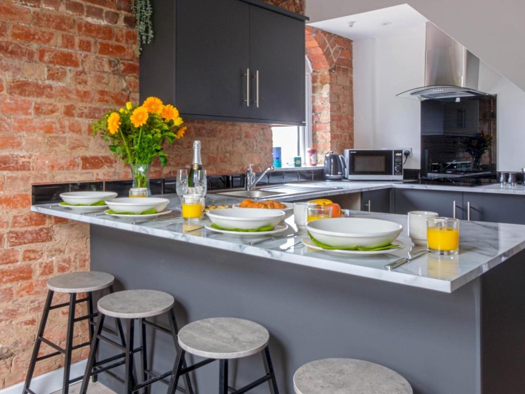 a kitchen with a counter with white plates and stools at Pass the Keys Wonderful historic conversion in Doncaster