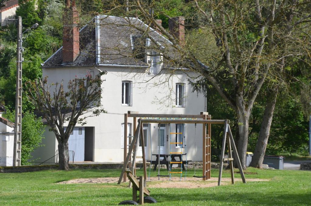 un parque infantil frente a una casa blanca en Au bord de l'eau, en Chambon-sur-Voueize