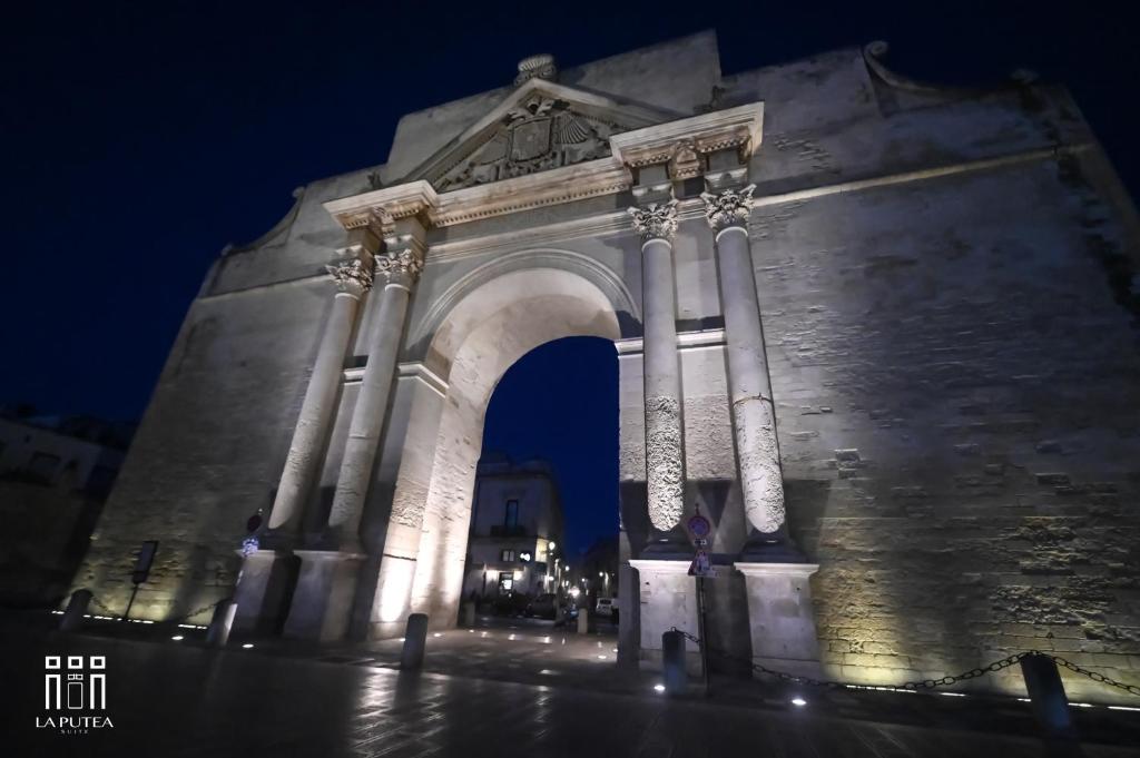 a stone arch with columns at night at LA PUTEA SUITE in Lecce