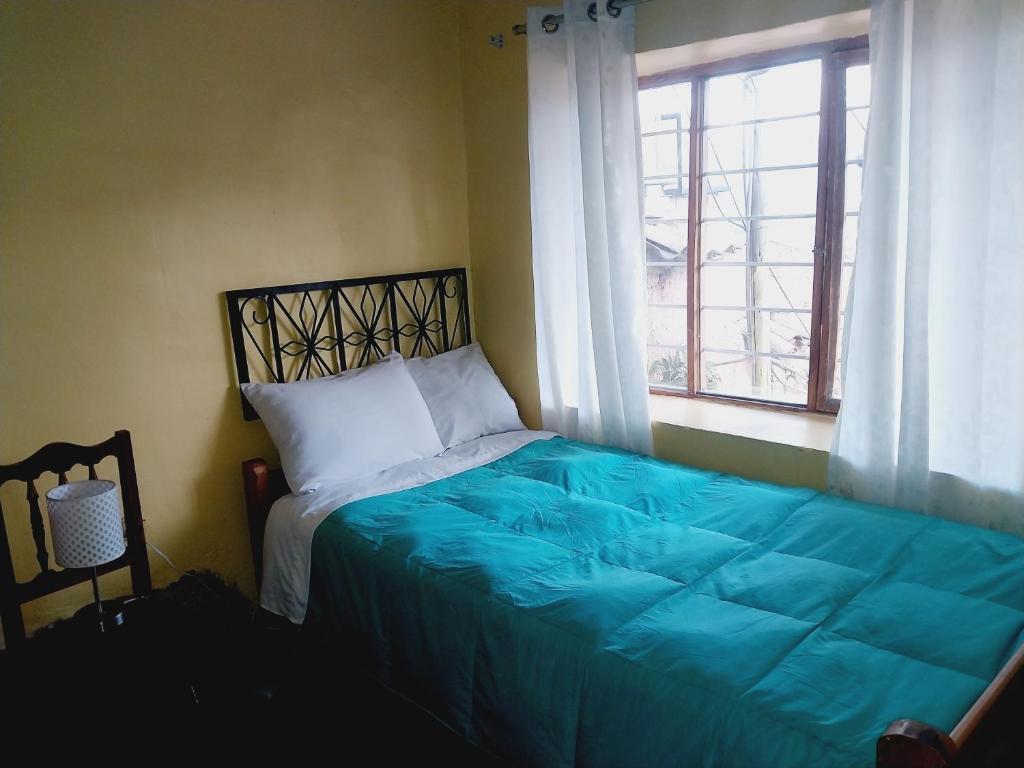 a bed in a bedroom with a blue blanket and a window at Walker Home San Blas in Cusco