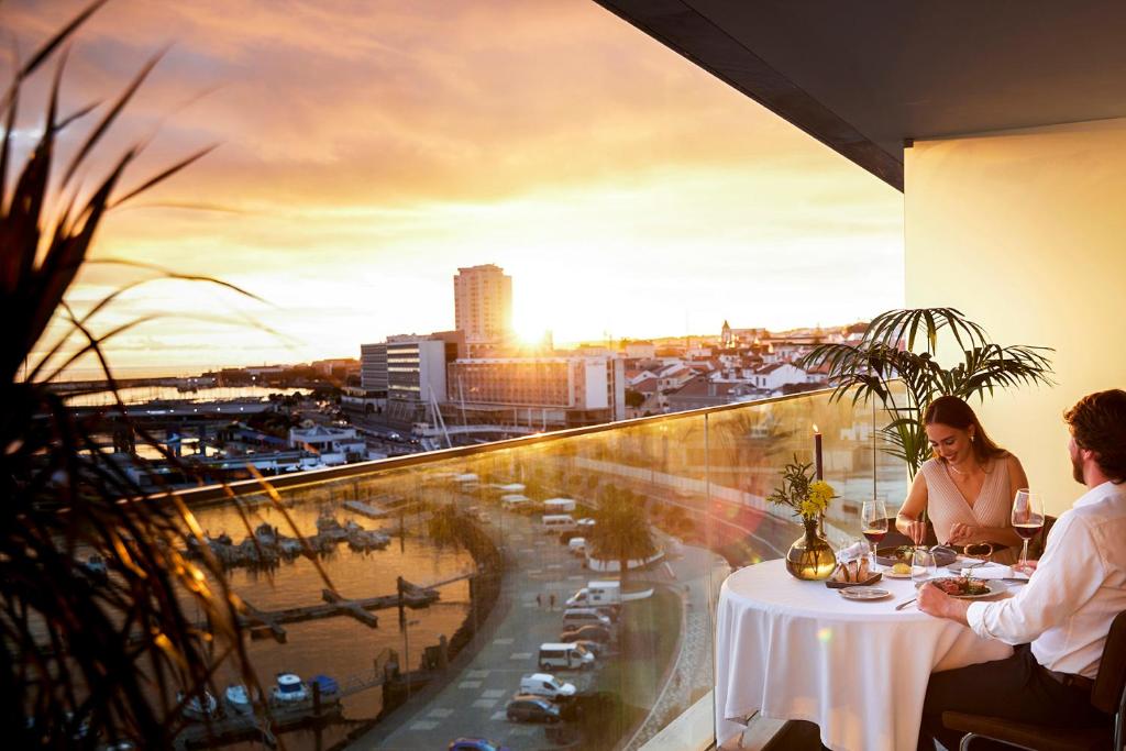 two people sitting at a table with a view of a city at Octant Ponta Delgada in Ponta Delgada