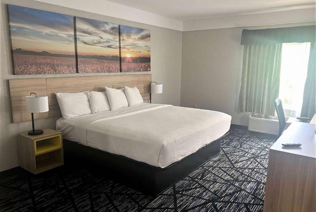 a hotel room with a large bed with two paintings on the wall at Days Inn by Wyndham Denham Springs-Baton Rouge East in Denham Springs