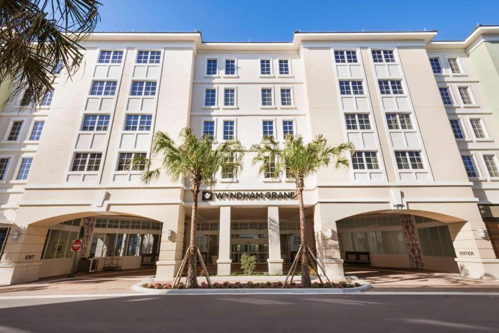 a large white building with palm trees in front of it at Wyndham Grand Jupiter at Harbourside Place in Jupiter