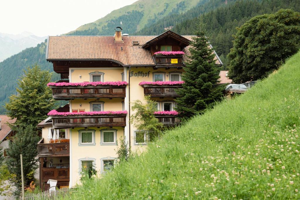 a building with flowers on the balconies on a hill at Gasthof Innerwalten in San Leonardo in Passiria