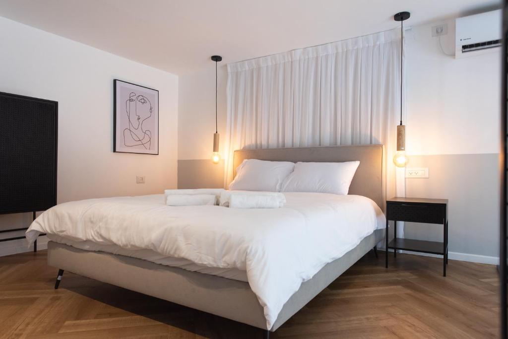 a bedroom with a large white bed with two pillows at PORT CITY HAIFA - Urbanic Loft in the Heart of Haifa's Downtown in Haifa