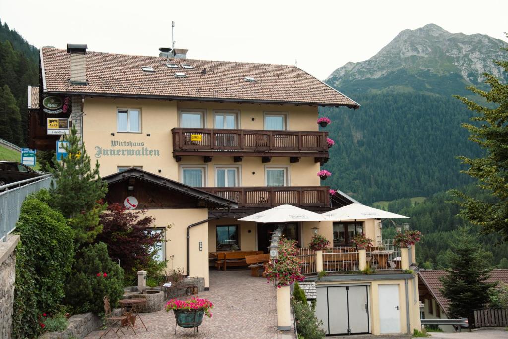 un grand bâtiment avec un balcon dans les montagnes dans l'établissement Gasthof Innerwalten, à San Leonardo in Passiria