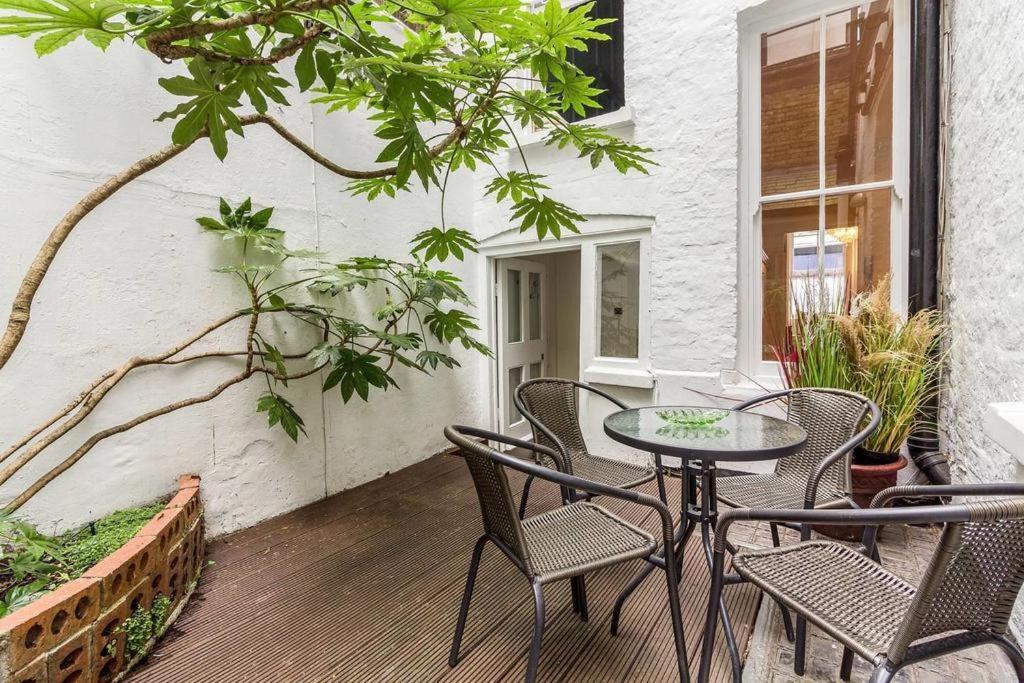 a patio with a table and chairs on a porch at Spacious Soho Home On Quaint Cobbled Street in London