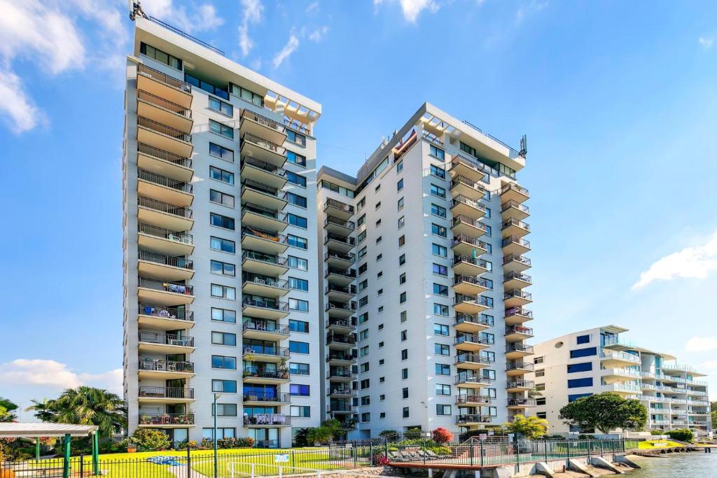 two tall buildings next to a body of water at Maroochydore Riverfront Apartment in Maroochydore