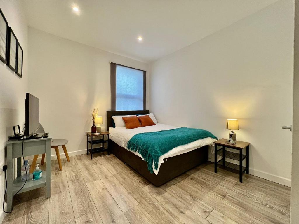 een slaapkamer met een bed, een bureau en een televisie bij Dunamis Staycation 5 in Croydon