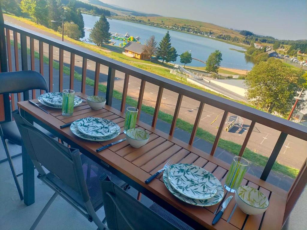 une table en bois avec des assiettes de nourriture sur un balcon dans l'établissement Appartement situé en plein centre à deux pas des pistes., à Besse-et-Saint-Anastaise