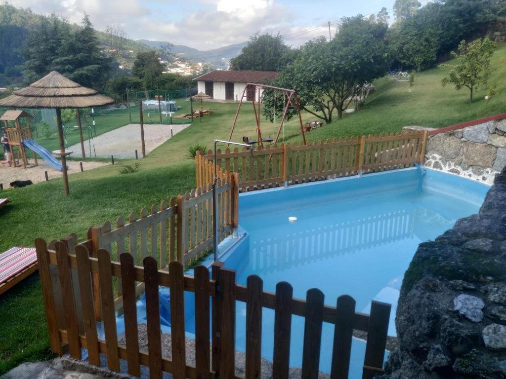 uma piscina com uma cerca de madeira e um parque infantil em Quinta dos Campos - Apartamento 2 em Braga