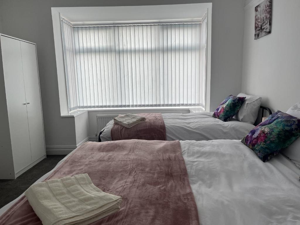 two beds in a room with a large window at Moorside House in Bolton