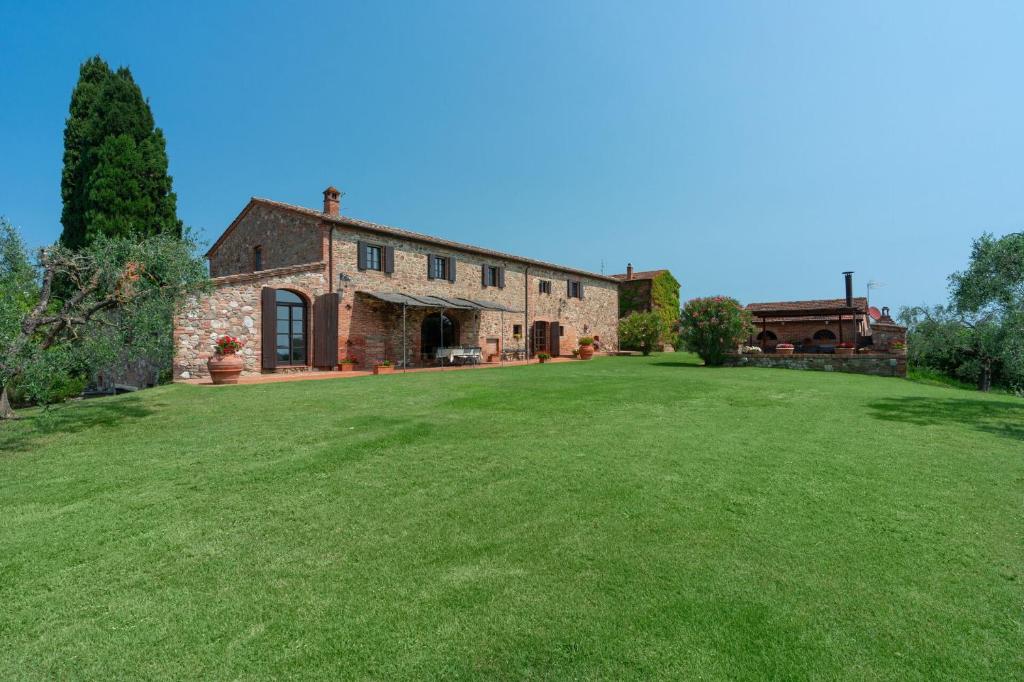 uma antiga casa de pedra com um grande jardim de relva em Podere Le Pozze em Sinalunga