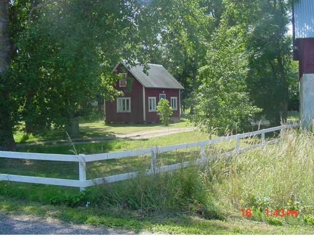 una cerca blanca frente a una casa roja en Sydöstra Gotland, en Hemse