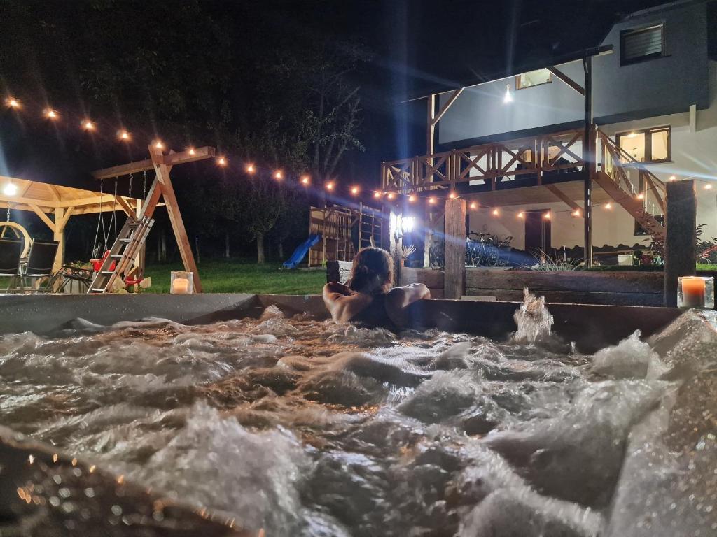 a woman is sitting in a water fountain at night at Beskidzki Zakątek Krynica-Zdrój in Krynica Zdrój