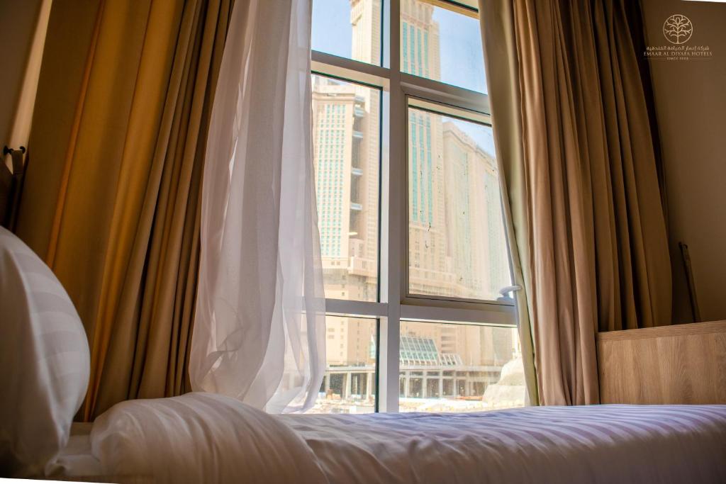 een slaapkamer met een raam met uitzicht op de stad bij Worth Elite Hotel in Mekka
