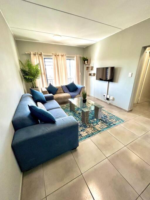 a living room with a blue couch and a table at The Place @ Mall of Africa in Midrand