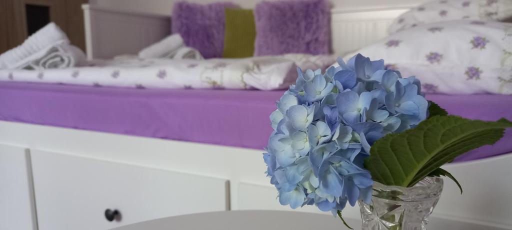 Garsonka ve Dvoře في دفور كرالوفي ناد لابيم: مزهرية مع الزهور الزرقاء على طاولة في غرفة النوم