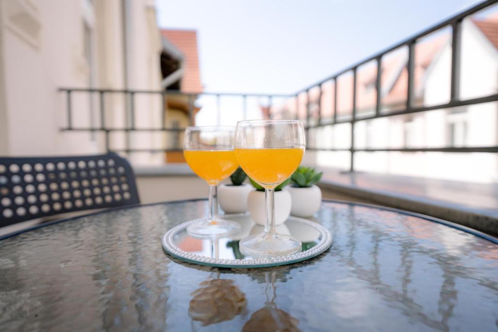 dwie szklanki soku pomarańczowego siedzące na stole w obiekcie Cosy Balcony Apartment w Grudziądzu