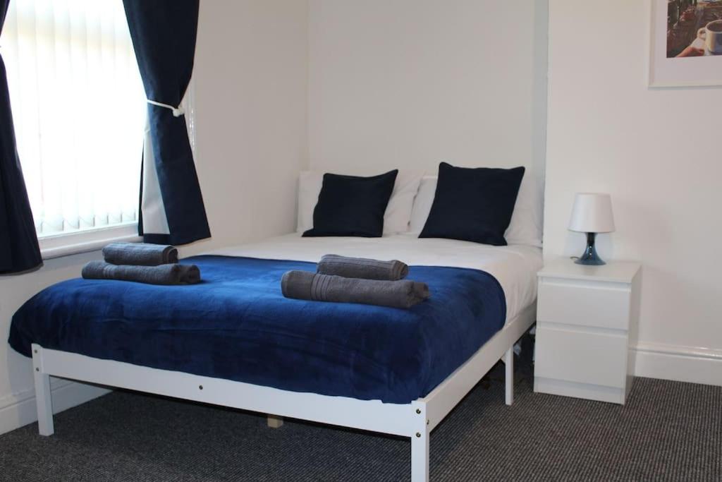 a bedroom with a bed with a blue blanket at Grove Bay Inn Home in Leeds - Harehills in Leeds