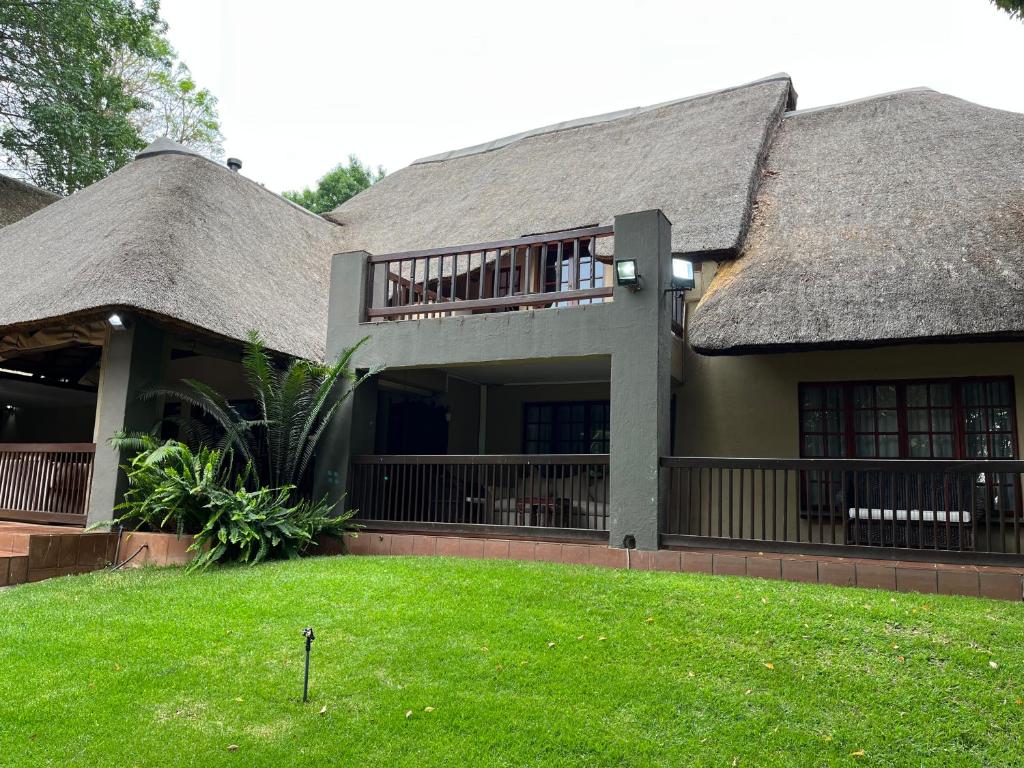 a house with a thatched roof and a yard at Monchique Boutique Guest House in Muldersdrift