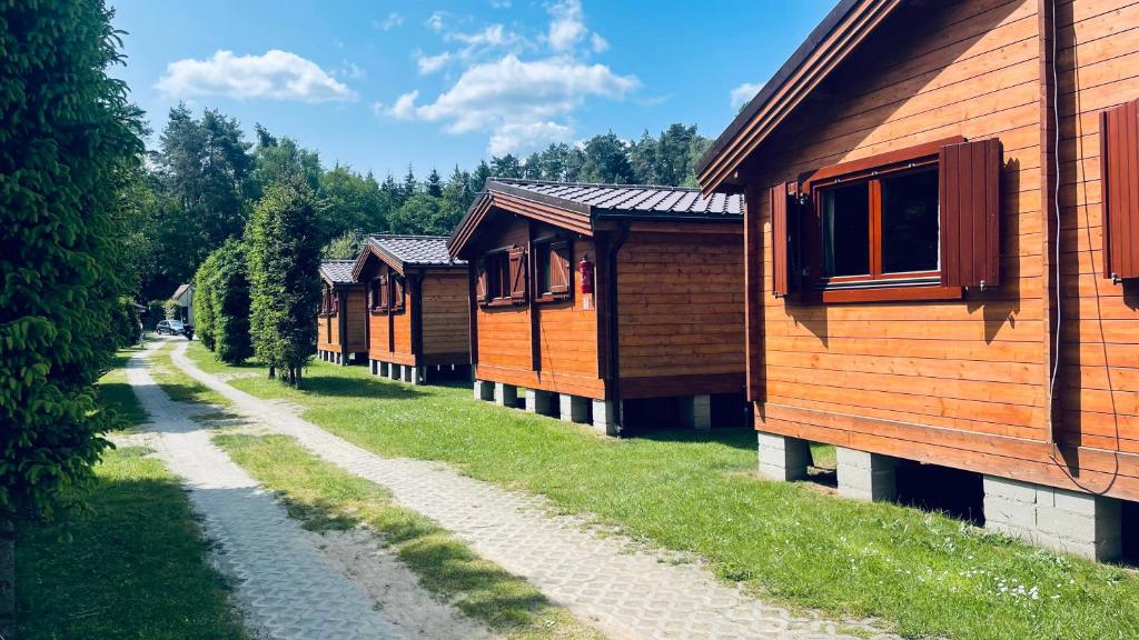 a row of wooden cabins parked next to a dirt road at Ośrodek Wypoczynkowy ADA in Niesulice