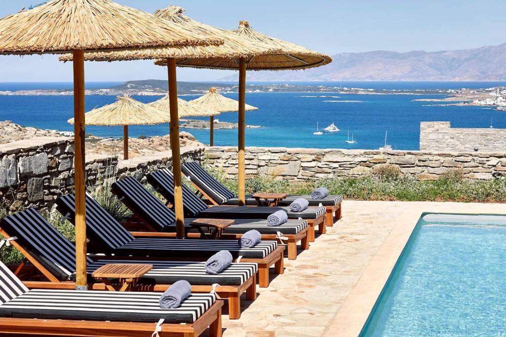 - une rangée de chaises longues avec des parasols et une piscine dans l'établissement Platinum Paros Villa - Villa Azure - 5 Bedrooms - Sea Views & Private Pool - Naoussa, à Kolympithres
