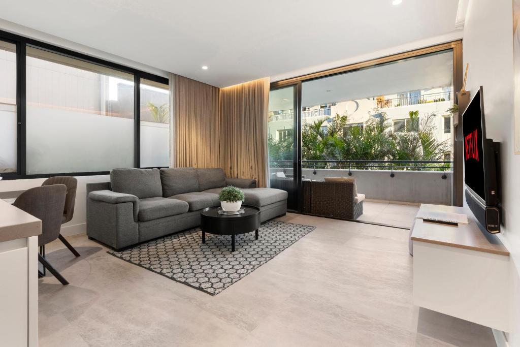 uma sala de estar com um sofá e uma televisão em THE SHORE: COOGEE BEACH em Sydney